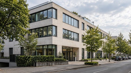 Fassade eines modernen Bürogebäudes mit hellem Naturstein und großen Fensterbändern